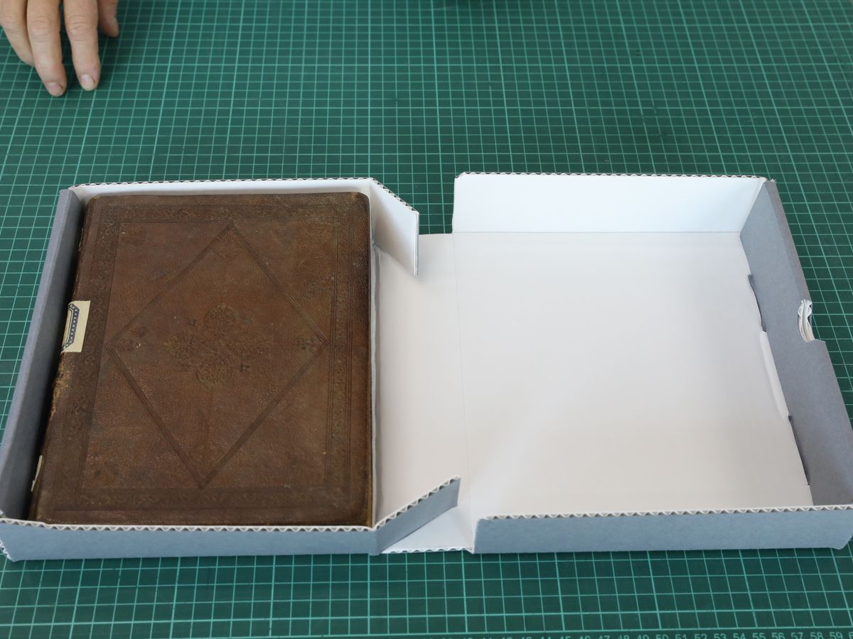 A leather-bound manuscript resting in a made-to-measure acid-free box.